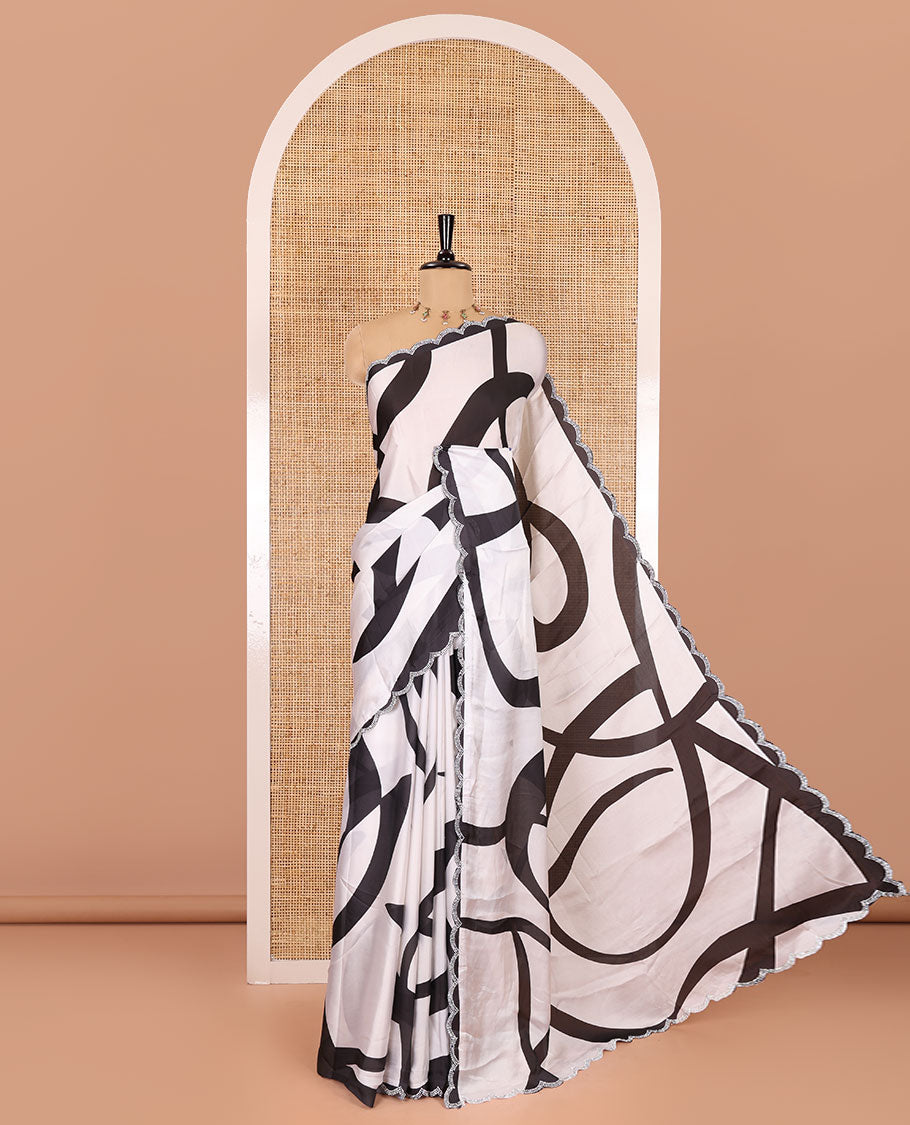 Cream and black abstract printed satin crepe saree, scallop jarkan stone work border, self-pallu, and a contrast printed blouse