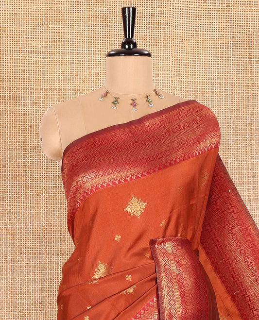 Rust Orange Kanchi Silk Saree Graced with Gold Zari Buttas Woven All Over Its Body, Complemented by Contrast Traditional Zari Design Border, Pallu Majestically Detailed with Intricate Zari Designs, and Paired with a Contrast Blouse