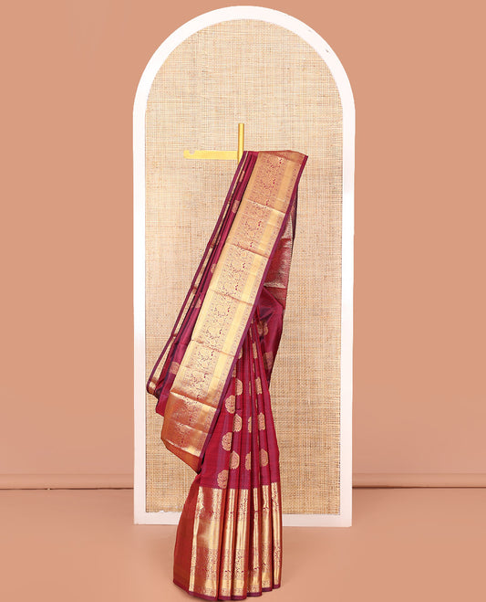Maroon Vasundhara Silk Saree Ornamented with Zari Buttas All Over Its Body, Highlighted by Zari Border of Rekku, Kodi Visiry, Mayil, and Kuyil Kann Designs, a Grand Pallu of Diagonal Stripes, and Paired with a Matching Blouse