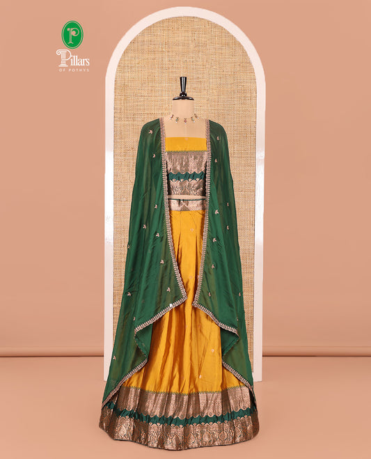 Yellow-Green Semi-Banarasi Half-Saree Subtly Sparkled with Zari Buttas on Its Skirt, Complemented by a Contrast Traditional Zari Temple Rettai Pettu Border, Paired with a Matching Blouse, and a Satin Georgette Embroidered Scallop Dhavani