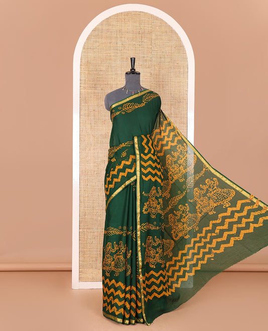 Green wax batik-style zig-zag printed pure cotton saree, gold zari piping border, human figurines batik printed pallu, and a matching blouse