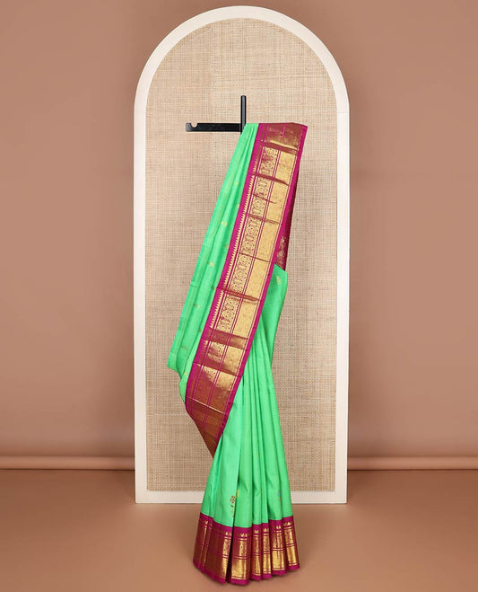 Green floral meena buttas Kanchipuram silksaree, contrast one-sided korvai border of thilakam mokku, manga & jaal & peacock inside palanquin design pallu