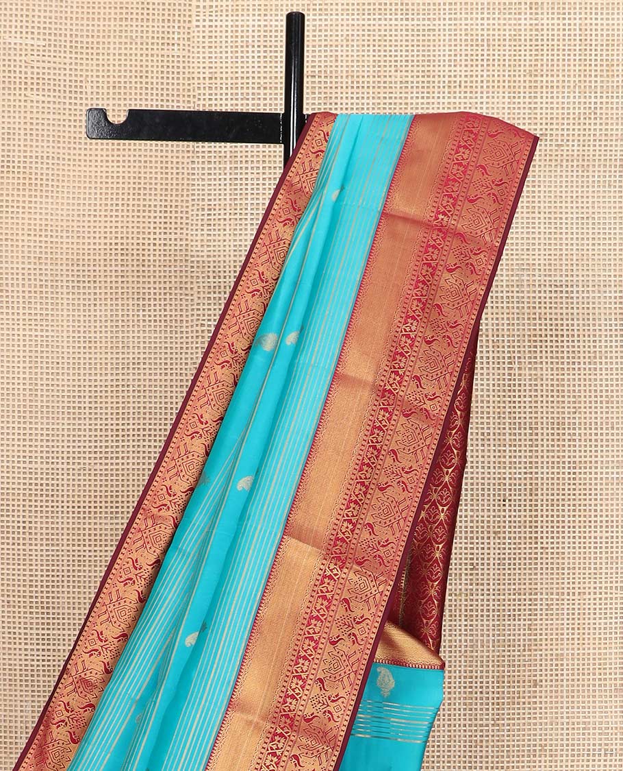 Blue zari buttas and striped Vasundhara silk mix saree, contrast border of thilakam mokku, mayil kann, paisa and paithani-style zari designs, and thilakam steeped pallu