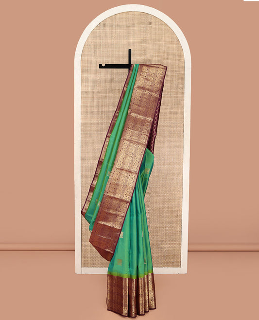 Sea Green Vasundhara Silk Saree, Accentuated with Zari Buttas All Over Its Body, Complemented by Contrast Border of Ara Bogudi, Banaras, Jada Nagam and Dhavana Kodi Designs, Pallu of Intricate Designs, and Paired with a Contrast Blouse