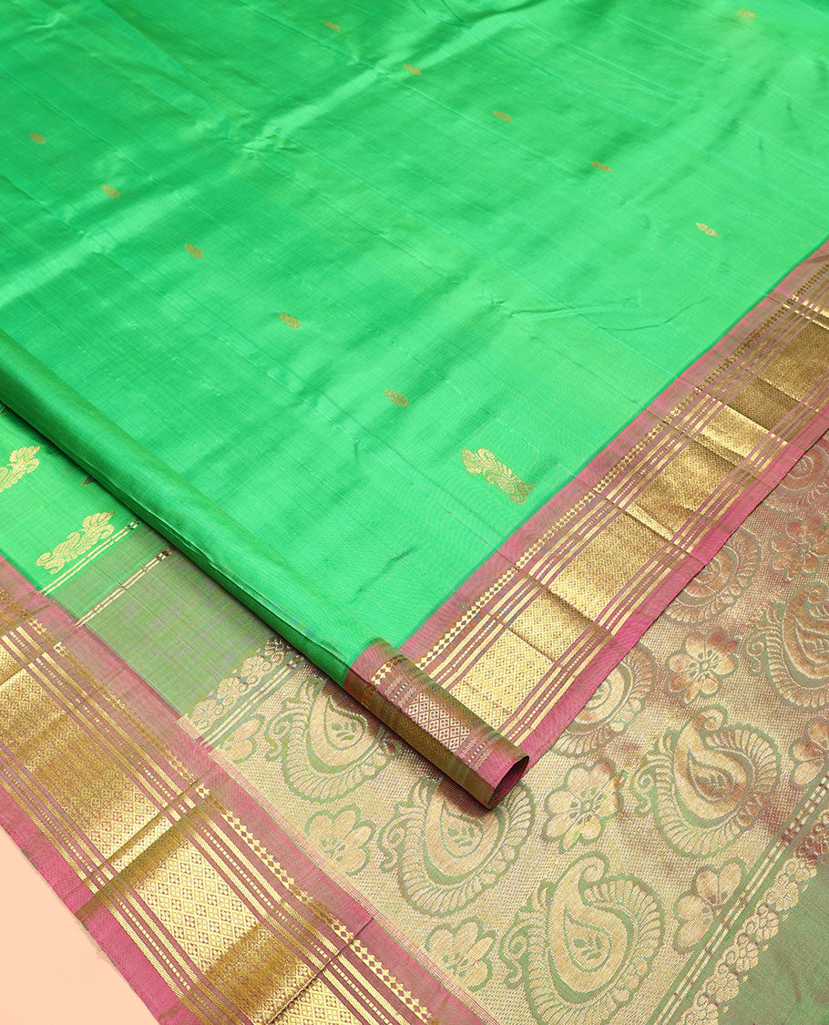 Green Kanchipuram Silk Saree, Adorned with Zari Buttas All Over Its Body, Complemented by a Contrast One-Sided Border of Panner Sombu, Banaras, Muthu, and Jaal Designs, Pallu of Floral Paisleys, and Comes Without a Blouse