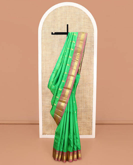 Green Kanchipuram Silk Saree, Adorned with Zari Buttas All Over Its Body, Complemented by a Contrast One-Sided Border of Panner Sombu, Banaras, Muthu, and Jaal Designs, Pallu of Floral Paisleys, and Comes Without a Blouse