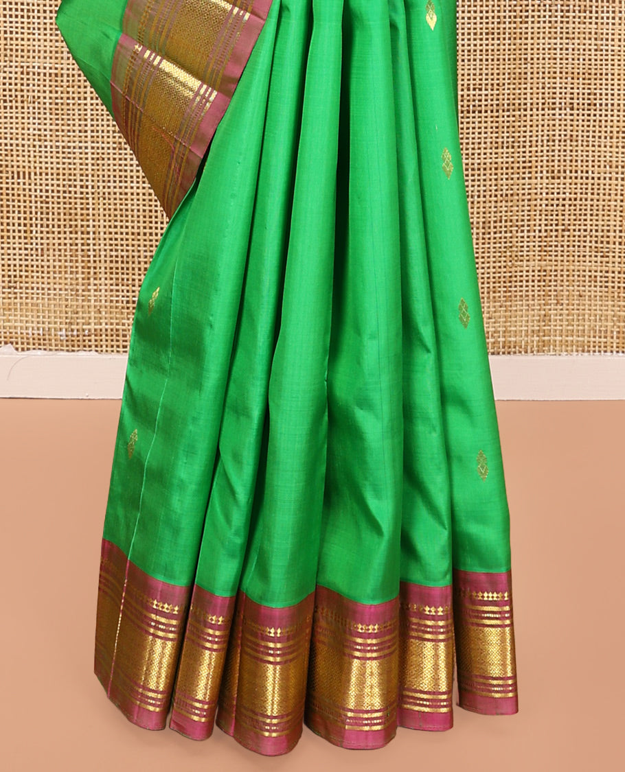 Green Kanchipuram Silk Saree, Adorned with Zari Buttas All Over Its Body, Complemented by a Contrast One-Sided Border of Panner Sombu, Banaras, Muthu, and Jaal Designs, Pallu of Floral Paisleys, and Comes Without a Blouse