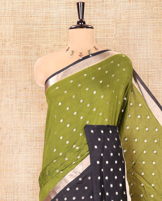 Olive Green Assam Silk Saree, Charmingly Accented with Zari Buttas on Its Body, Complemented by Contrast Border Steeped with Zari Buttas, Pallu Steeped with Gleaming Zari Stripes and Buttas, and Paired with a Contrast Blouse