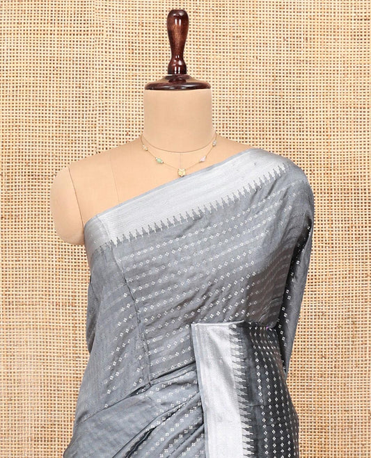 Grey Banana Pith Saree, Subtly Sparkled with Buttas All Over Its Body, Highlighted by Zari Temple Border, Gleaming Pallu Steeped with Stripes, and Paired with a Matching Blouse