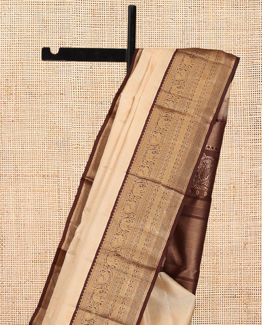 Sandal Vasundhara Silk Saree, Sparsely Sparkled with Zari Checks and Mayil Buttas, a Contrast Border of Thilakam Mokku, Banaras, Neli, Mayil, Yaanai, Mayil Kann, and Ara Maadam Designs, Grand Pallu, and a Contrast Blouse