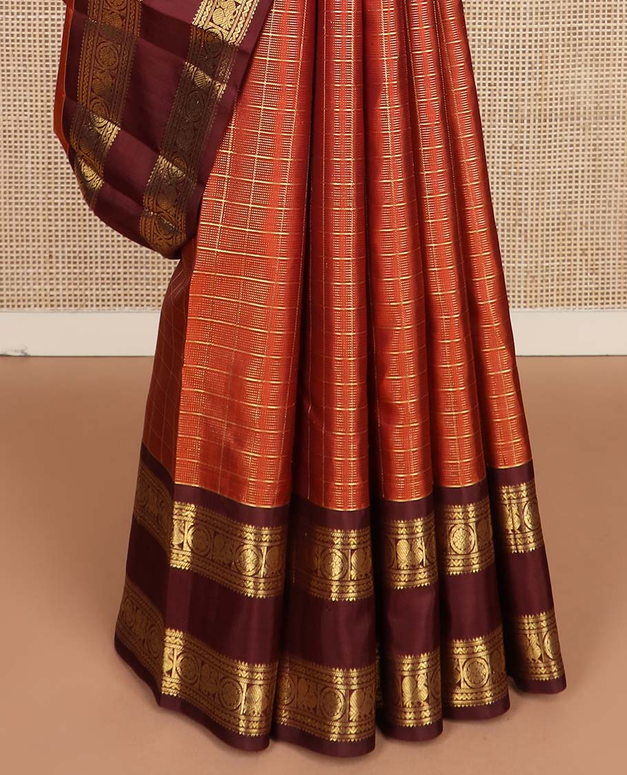 Orange zari checked Kanchipuram silk saree, contrast rettai pettu border of rekku, banaras, neli, and mayil chakram designs, and pallu of lavangam designs