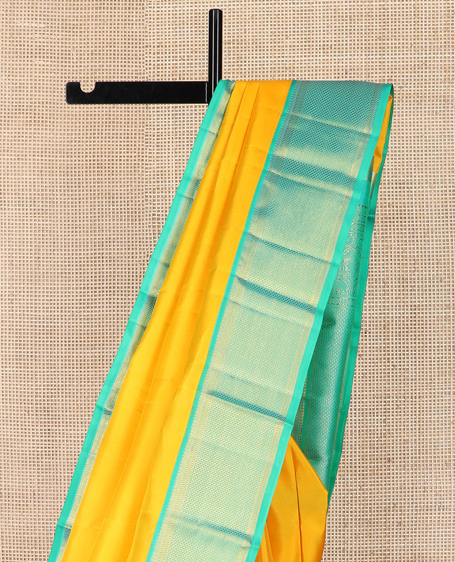 Yellow plain Kanchipuram silk saree, contrast border of salngai, muthu, and ara maadam designs, and intricate pallu