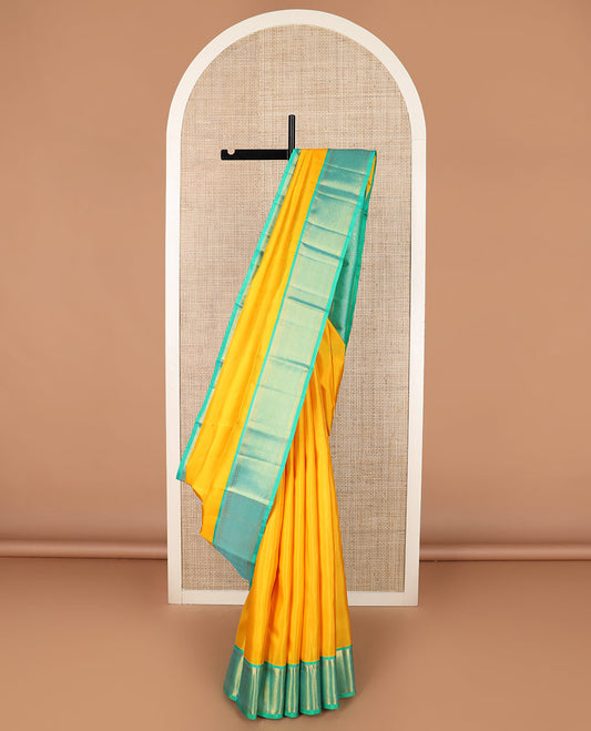 Yellow plain Kanchipuram silk saree, contrast border of salngai, muthu, and ara maadam designs, and intricate pallu