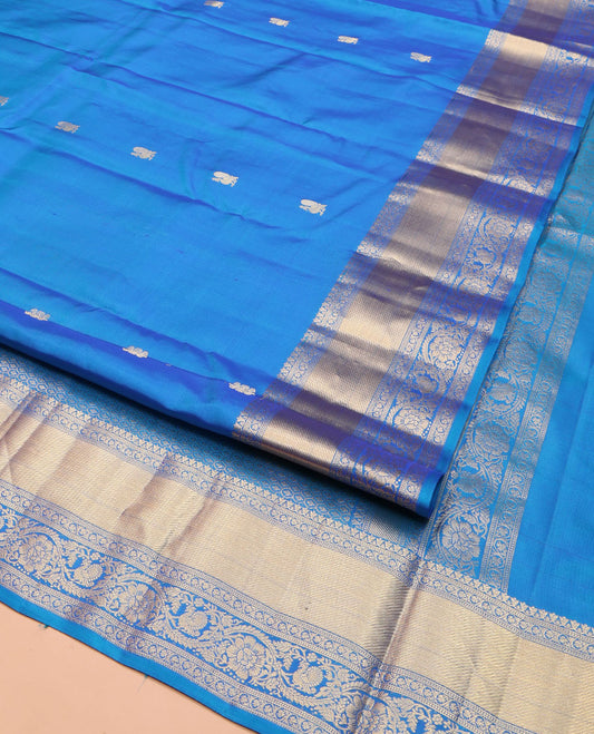 Blue Vasundhara Silk Saree, Mesmerized with Zari Buttas All Over Its Body, Highlighted by a Zari Border of Kodi Visiry, and Mayil Designs, Grand Jaal Pallu, and Paired with a Matching Blouse