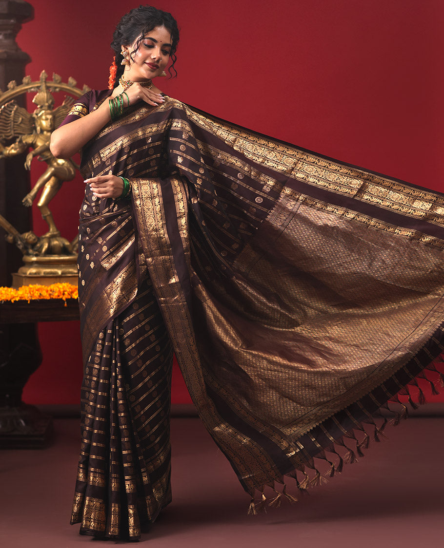 Brown Vasundhara Silk Saree, Enriched with Annam Chakram Buttas and Zari Stripes, Highlighted by Zari Rettai Pettu Border of Ara Bogudi, Muthu, Banaras, Yaanai, and Chakram Designs, Gleaming Jaal Design Woven Pallu, and Paired with a Matching Blouse