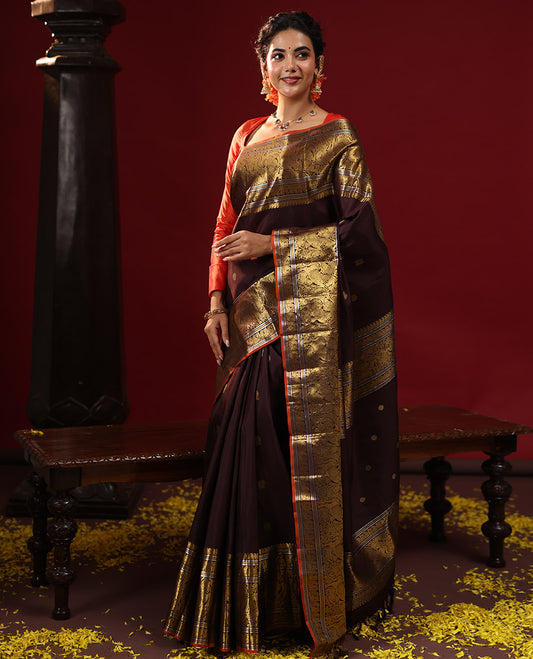 Brown Kanchipuram Silk Saree Embellished with Zari Buttas All Over the Body, Complemented by Zari Border of Manga Mokku, Banaras, Muthu, Mayil, Kuthirai, and Yaali Designs, Gracefully Decked Up Pallu, and Paired with a Matching Blouse