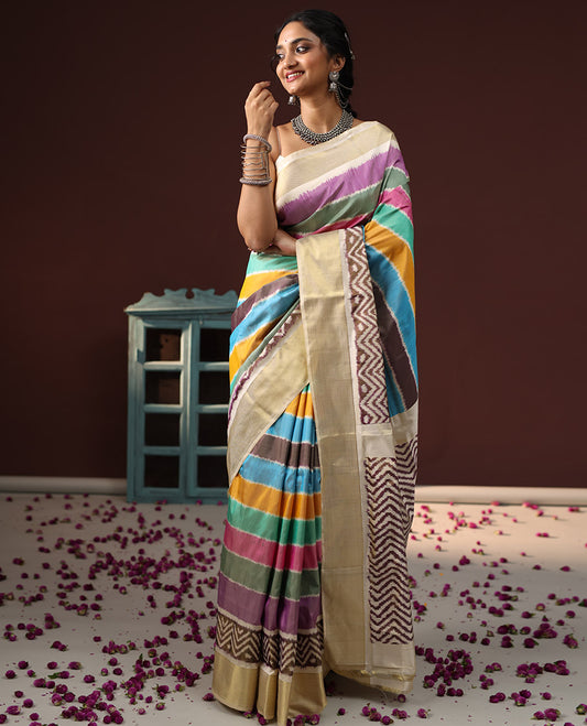 Multi-Color Ikkat Silk Saree Adorned with Kaleidoscope-Colored Stripes All Over Its Body, Complemented by Contrast Chevron Zari Border, Pallu Depicts Ikkat Woven Chevron Patterns, and Paired with a Matching Blouse