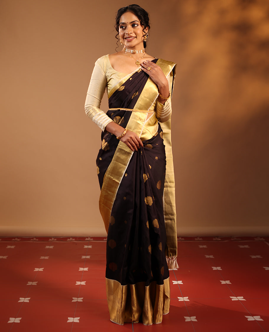 Dark Chocolate Brown Vasundhara Silk Saree Highlighted with Zari Buttas, Decked Up with a Contrast Border Featuring Rekku, Mayil Kann, Mayil, and Rudraksham Designs, Zari-Elevated Pallu, and Complemented with a Zari-Embellished Blouse