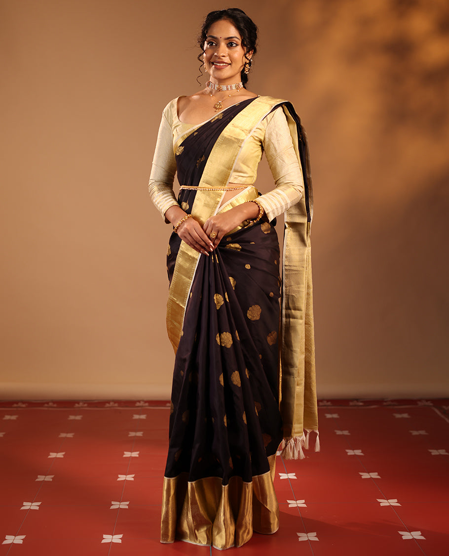 Dark Chocolate Brown Vasundhara Silk Saree Highlighted with Zari Buttas, Decked Up with a Contrast Border Featuring Rekku, Mayil Kann, Mayil, and Rudraksham Designs, Zari-Elevated Pallu, and Complemented with a Zari-Embellished Blouse