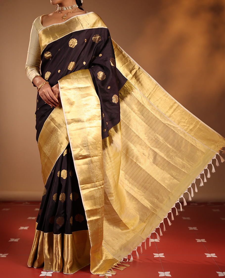 Dark Chocolate Brown Vasundhara Silk Saree Highlighted with Zari Buttas, Decked Up with a Contrast Border Featuring Rekku, Mayil Kann, Mayil, and Rudraksham Designs, Zari-Elevated Pallu, and Complemented with a Zari-Embellished Blouse