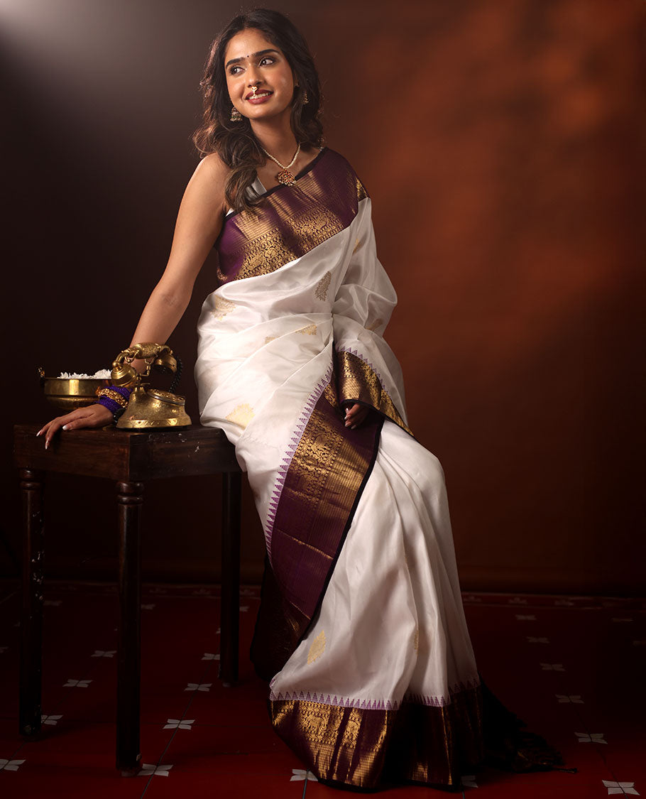 White Silk Saree Highlighted with All-Over Zari Buttas, Contrast Border Features Thazampoo Rekku, Yaanai, Mayil, and Muthu Designs, with a Zari-Enriched Jaal Pallu