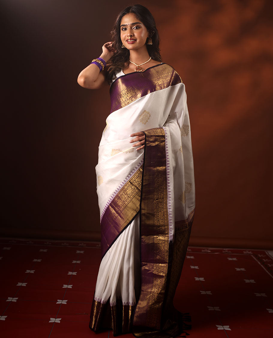 White Silk Saree Highlighted with All-Over Zari Buttas, Contrast Border Features Thazampoo Rekku, Yaanai, Mayil, and Muthu Designs, with a Zari-Enriched Jaal Pallu