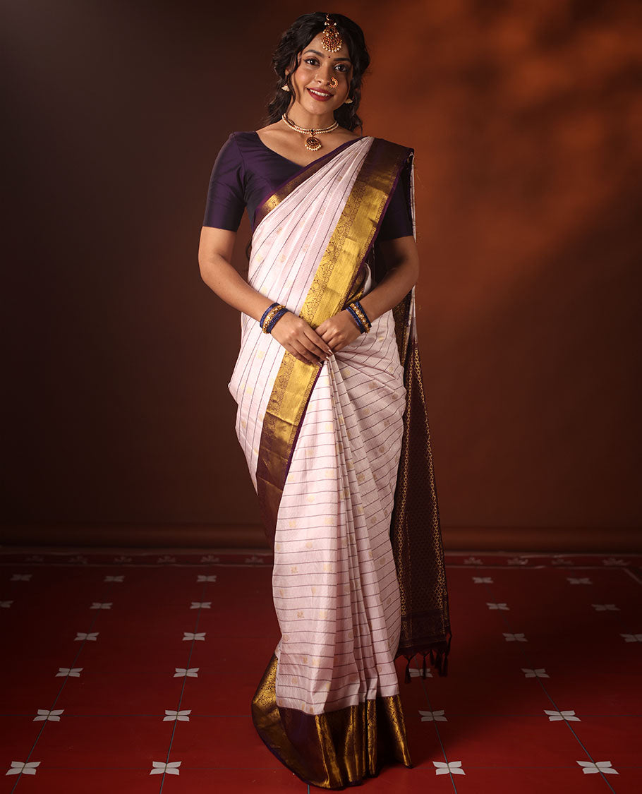 White silk saree adorned with Mayil Chakram, Neli, and Muthu stripes, featuring a contrast border with Laddu Kamalam, Mayil, Yaali, and Mayil Kann designs, along with a Jaal design pallu