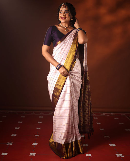 White silk saree adorned with Mayil Chakram, Neli, and Muthu stripes, featuring a contrast border with Laddu Kamalam, Mayil, Yaali, and Mayil Kann designs, along with a Jaal design pallu