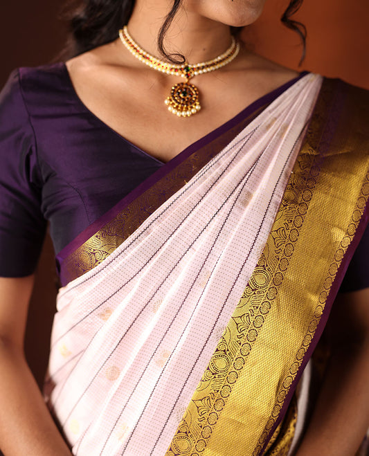 White silk saree adorned with Mayil Chakram, Neli, and Muthu stripes, featuring a contrast border with Laddu Kamalam, Mayil, Yaali, and Mayil Kann designs, along with a Jaal design pallu