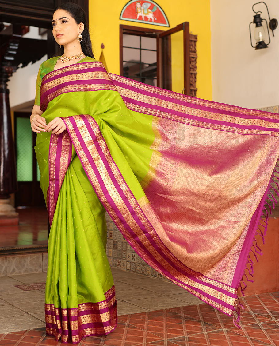 Parrot Green Vasundhara Silk Saree Richly Detailed with Zari Buttas, Complemented with Varisai Pettu Border Featuring Rekku, Muthu, Banaras, Rudraksham, and Mayil Designs, Majestically Zari Woven Pallu, and a Contrast Blouse