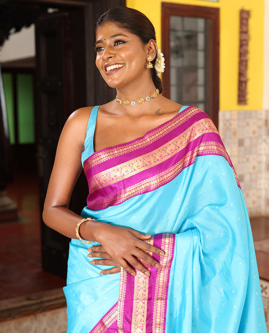 Blue Vasundhara Silk Saree Gracefully Embellished with Zari Buttas, Complemented by a Varisai Pettu Border Featuring Rekku, Muthu, Banaras, Rudraksham, and Mayil Designs, Majestically Woven with a Zari-Designed Pallu, and Paired with a Contrast Blouse