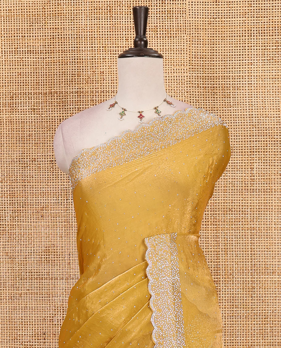 Mustard Swarovski crystal stone embedded fendy chiffon saree, scallop Swarovski stone embroidered border, and contrast plain blouse