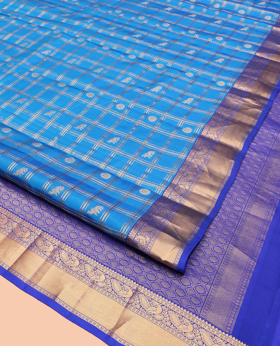 Blue Vasundhara Lite-Silk Mix Saree, Spotlighted with Yaanai, and Chakram Butta Enclosed Checks, Complemented by a Contrast Border of Thilakam, Poun, and Mayil Designs, Pallu Highlighted by Geometric Designs, and Paired with a Contrast Blouse