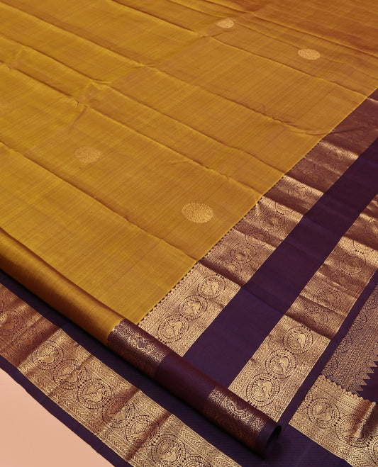 Mustard Kanchipuram Silk Saree, Embellished with Round Buttas All Over Its Body, Complemented by a Contrast Rettai Pettu Border of Thilakam Mokku, Muthu, Kathir, and Round Mayil Designs, Grand Jaal Pallu, and Paired with a Contrast Blouse