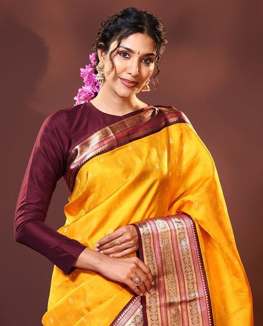 Yellow Silk Saree Subtly Sparkled with Buttas Enclosed Checks All Over Its Body, Complemented by Contrast  Border of Rekku, Chakram, and Jada Nagam Designs, a Grandly Woven Pallu of Intricate Mughal Designs, and Paired with a Contrast Blouse