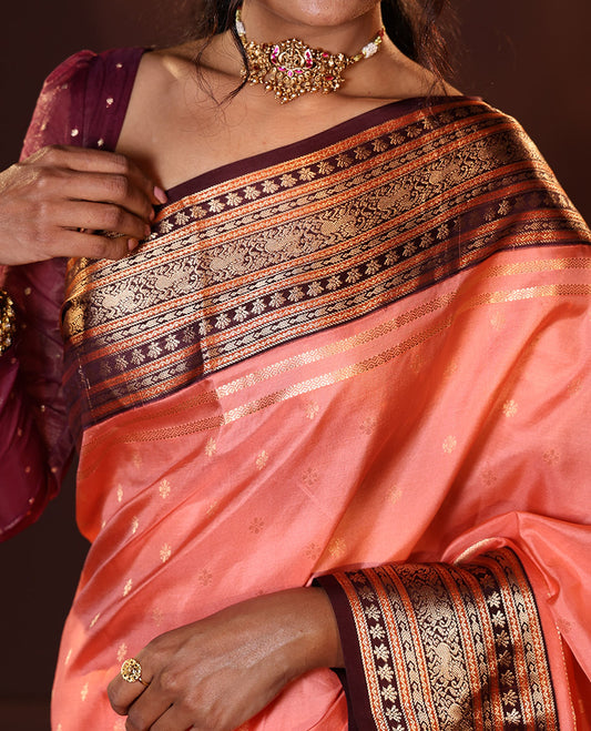 Peach Vasundhara Silk Saree Spotlighted with Zari Buttas All Over Its Body, Complemented by Contrast Border of Banaras, Neli, Floral, and Yaali Designs, Grandly Decked Up Pallu of Intricate Designs, and Paired with a Contrast Blouse