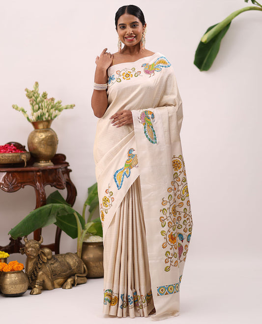 Enthralling cream kalamkari hand-painted silk saree featuring zari buttas with kalamkari floral vine, peacock, deer, & elephant motifs