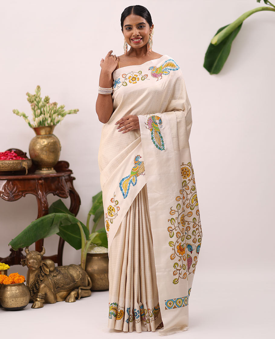 Enthralling cream kalamkari hand-painted silk saree featuring zari buttas with kalamkari floral vine, peacock, deer, & elephant motifs