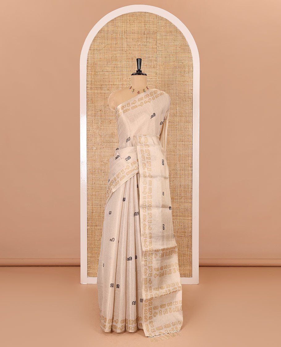 Cream-mustard Malayalam letter printed tissue saree, self-border and pallu steeped with Malayalam letter motifs, and a contrast plain blouse
