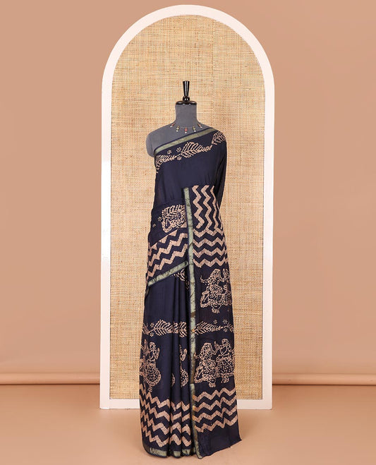 Navy blue wax batik-style zig-zag printed pure cotton saree, gold zari piping border, human figurines batik printed pallu, and a matching blouse