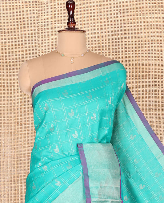 Turquoise Kuppadam Cotton Saree, Subtly Woven with Zari Butta Enclosed Checks on Its Body, Highlighted by Zari Bavanji Border, Complemented by Contrast Intricately Designed Pallu, and Paired with a Contrast Blouse