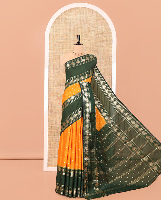 Orange Art Mysore Silk Saree, Decked Up with Zari Buttas All Over Its Body, Complemented by a Contrast Rettai Pettu Border of Two-Headed Eagle Designs, Pallu Steeped with Buttas and Stripes, and Paired with a Contrast Blouse