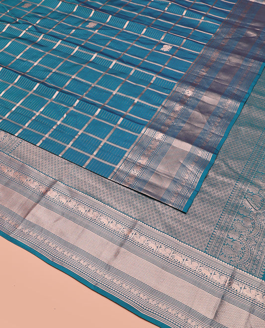 Blue Vasundhara Silk Saree Beautifully Bedecked with Medium Zari Checks, Highlighted by a Zari Border of Salngai, Mayil, Yaanai, Muthu, and Mayil Kann Designs, Delicately Woven Pallu, and Paired with a Matching Blouse