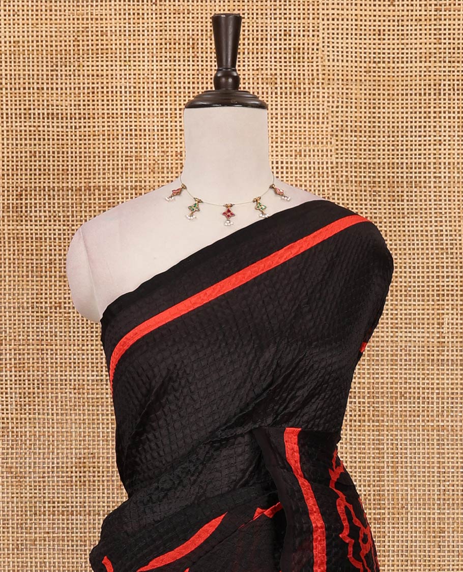Black-base crushed litchi saree features fancy red color floral printed body, printed piping border & pallu