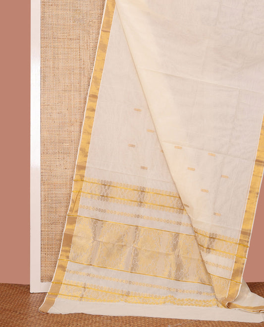 Cream Kerala Cotton Saree Mesmerized with Zari Buttas All Over Its Body, Bavanji Border, Intricately Woven Pallu, and Paired with a Matching Blouse