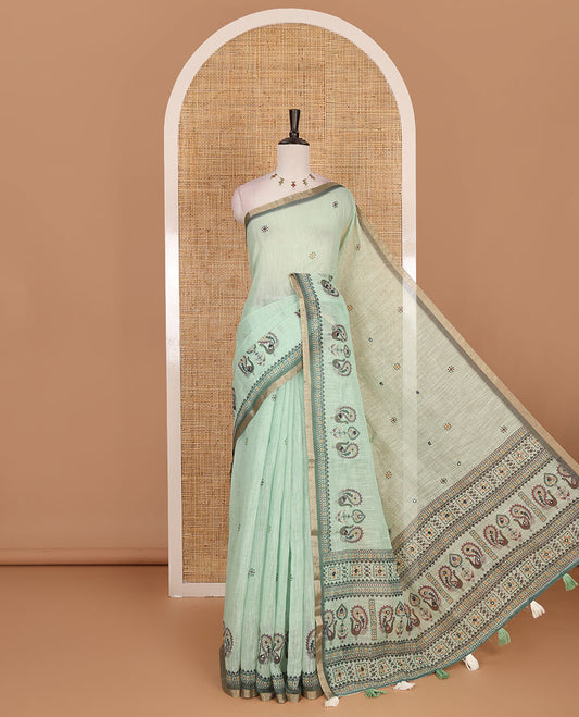 Green buttas with mirror work linen saree, zari border with peacock motifs print, printed mirror work pallu, and matching blouse