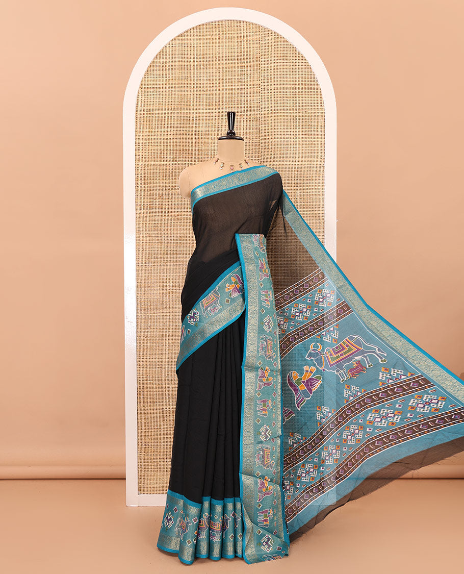Black embossed moss chiffon saree, contrast zari and colorfully printed border and pallu of human figurines and Pichwai cows, and embossed blouse