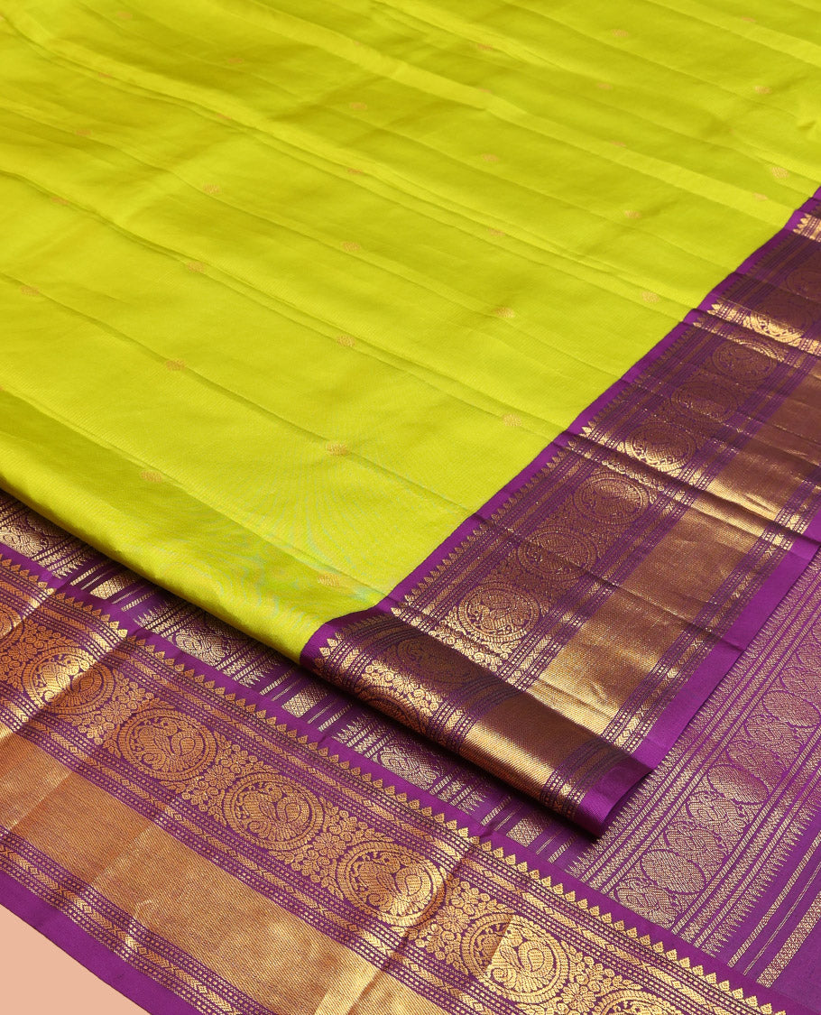 Parrot Green Vasundhara Silk Saree, Enriched with Sparse Stripes and Zari Buttas, Complemented by a Contrast Border of Thilakam, Banaras, Muthu, and Round Mayil Designs, Pallu Steeped with Traditional Designs, and Paired with a Contrast Blouse