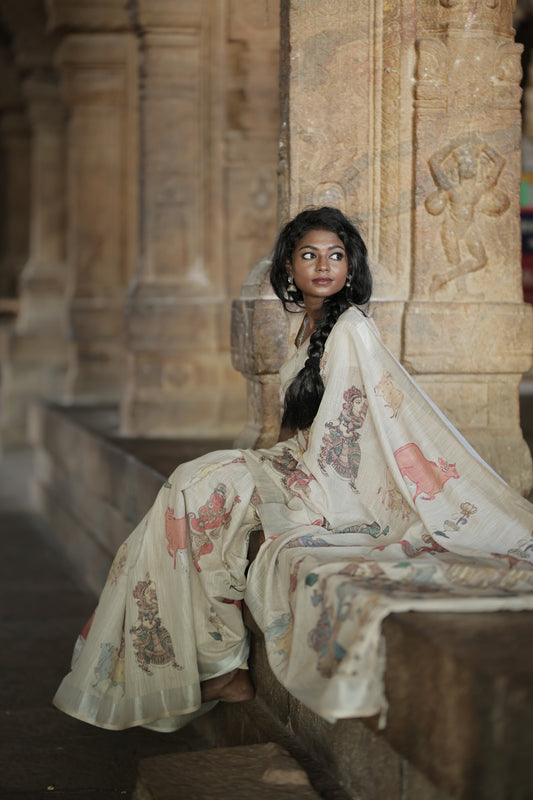 Cream Linen Saree Features Ancient Human Figurines, Floral, and Pichwai Cow, a Zari Border, Kalamkari Pallu, Matching Blouse