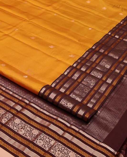 Yellow Vasundhara Silk Saree, Richly Detailed with Zari Buttas All Over Its Body, Complemented by a Contrast Border of Thilakam, Neli, Laddu Kamalam, and Kodi Visiry Designs, Pallu of Butta Enclosed Checks, and Paired with a Contrast Blouse